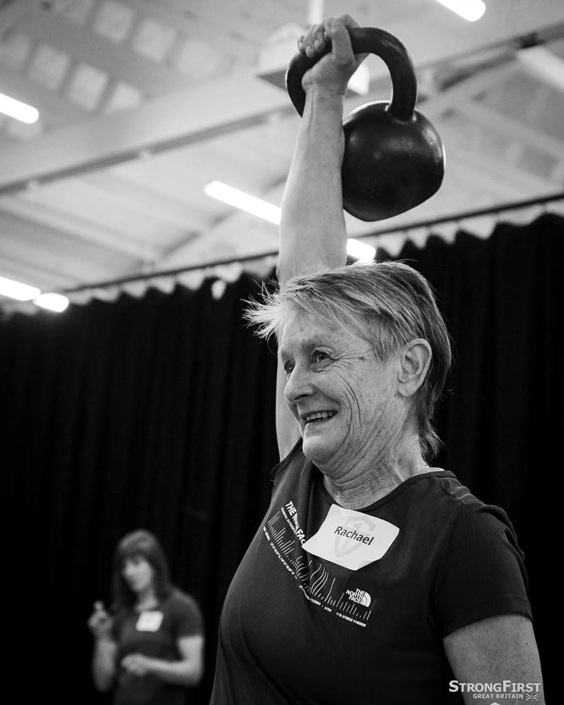 Rachael smiling while holding a kettlebell overhead